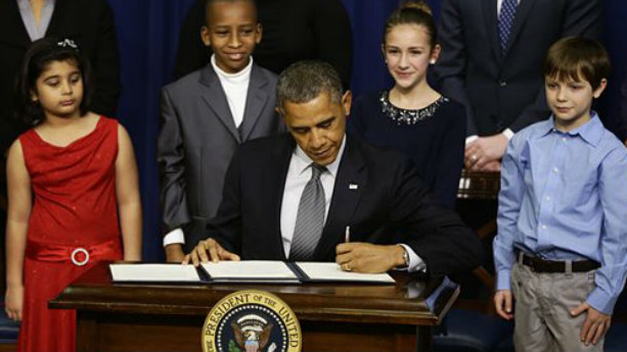 De izq. a der. Hinna Zeejah (8 años), Taejah Goode (10), Julia Stokes (11) y Grant Fritz (8), quienes escribieron cartas a Obama acerca del tiroteo en la escuela de Newtown, Connecticut, acompañan al mandatario mientras firma las medidas para restringir la venta y posesión de armas de fuego.
