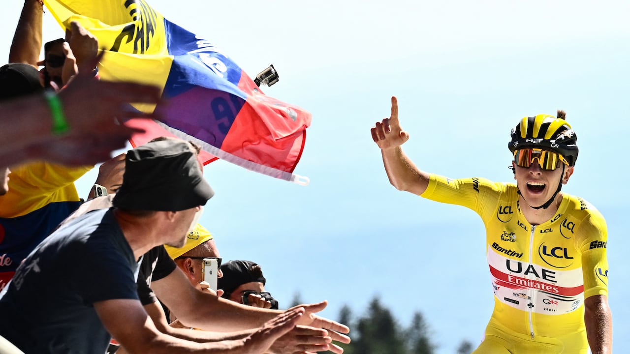 UAE Team Emirates team's Slovenian rider Tadej Pogacar wearing the overall leader's yellow jersey (R) celebrates as cycles past the finish line to win the 7th stage of the 109th edition of the Tour de France cycling race, 176,3 km between Tomblaine and La Super Planche des Belles Filles, in eastern France, on July 8, 2022. (Photo by Marco BERTORELLO / AFP)