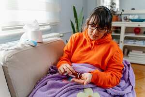 Sickness, seasonal virus problem concept. Woman being sick having flu lying on sofa looking at temperature on thermometer. Sick woman lying in bed with high fever. Cold flu and migraine.