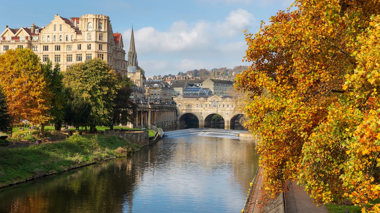 Los emblemáticos lugares de Pulteney Weir y el puente Pulteney, rodeados de árboles con los vivos colores del otoño, junto al río Avon en la ciudad de Bath.