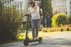 mujer de negocios joven en patineta eléctrica, movilidad, transporte.