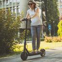 mujer de negocios joven en patineta eléctrica, movilidad, transporte.