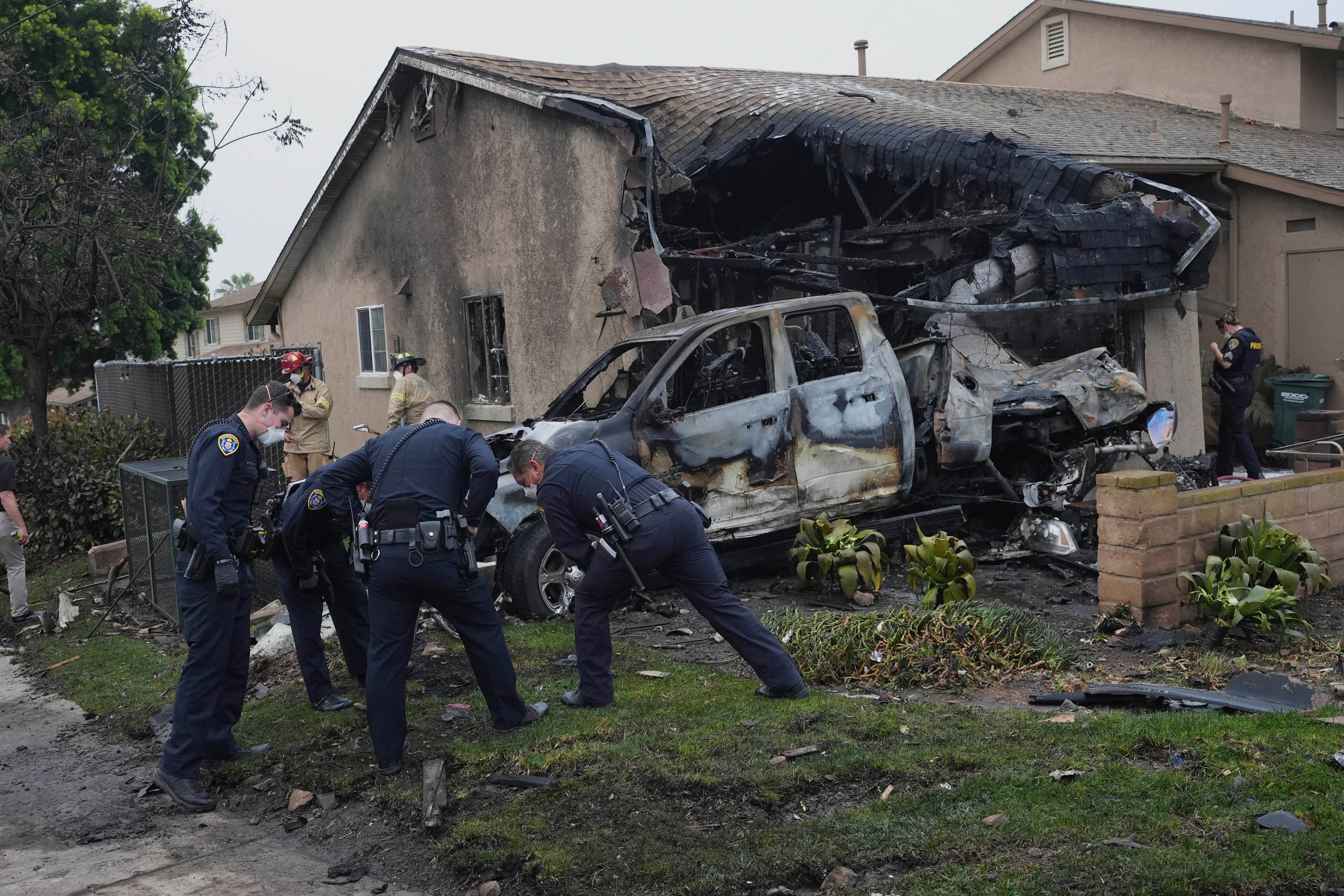 Authorities work the scene where a small plane crashed into a San Diego neighborhood, setting several homes on fire and forcing evacuations along several blocks early Thursday, May 22, 2025. (AP Photo/Gregory Bull)