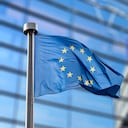 Banderas de la Unión Europea frente al Parlamento Europeo borroso en Bruselas, Bélgica