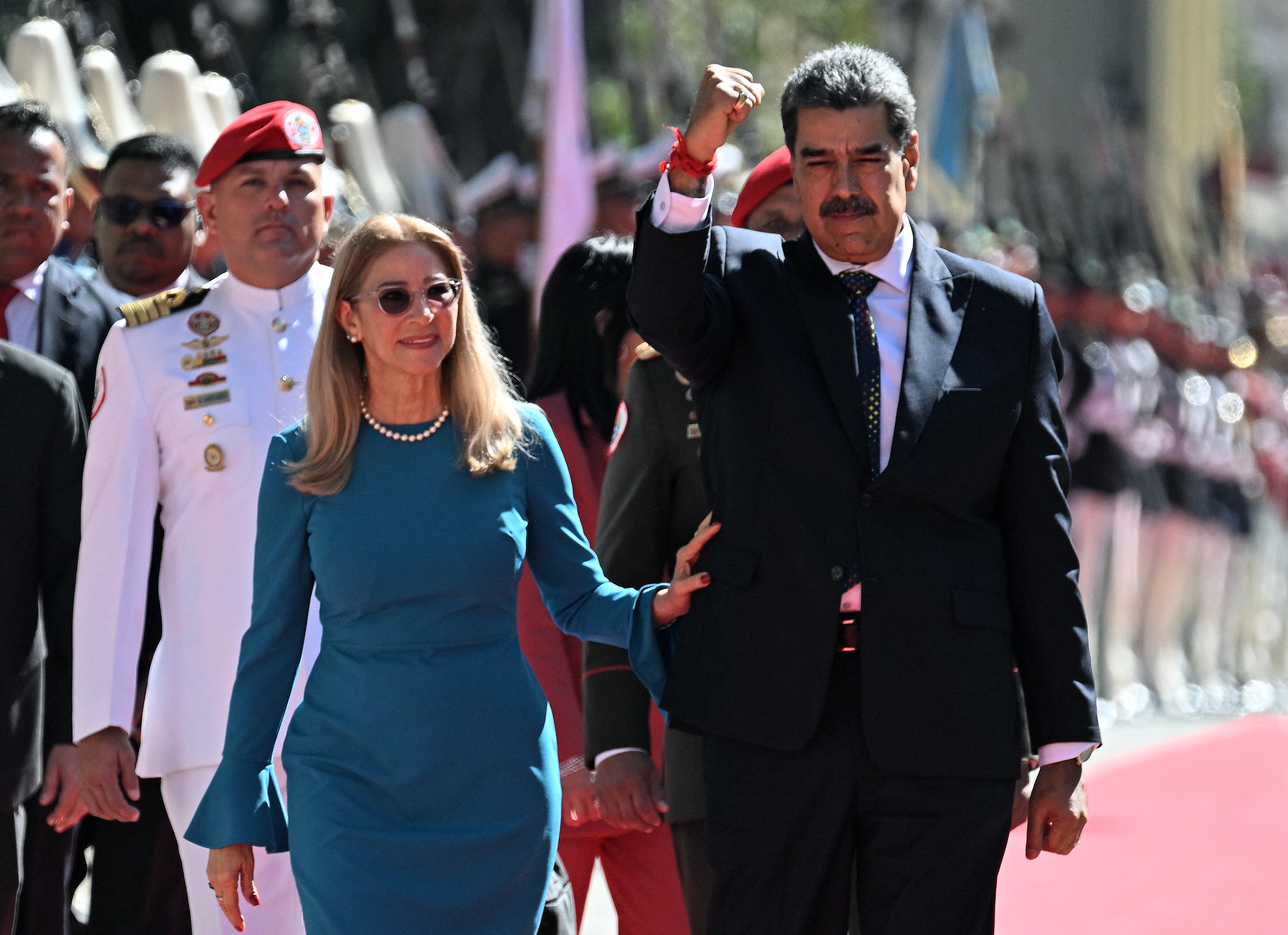 Venezuela's President Nicolas Maduro (R) gestures next to First Lady Cilia Flores on arrival at the Capitolio for the presidential inauguration, in Caracas on January 10, 2025. Maduro, in power since 2013, will take the oath of office for a third term despite a global outcry that brought thousands out in protest on the ceremony's eve. (Photo by Federico PARRA / AFP)