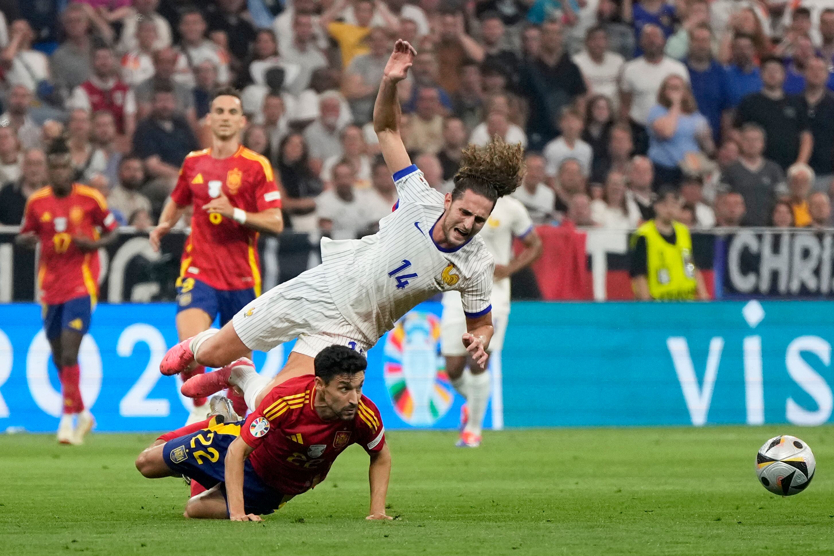 El español Jesús Navas, en el suelo, hace una falta al francés Adrien Rabiot al ver una tarjeta amarilla durante un partido de semifinal entre España y Francia en el torneo de fútbol Euro 2024 en Munich, Alemania, el martes 9 de julio de 2024. (Foto AP/Matthias Schrader )