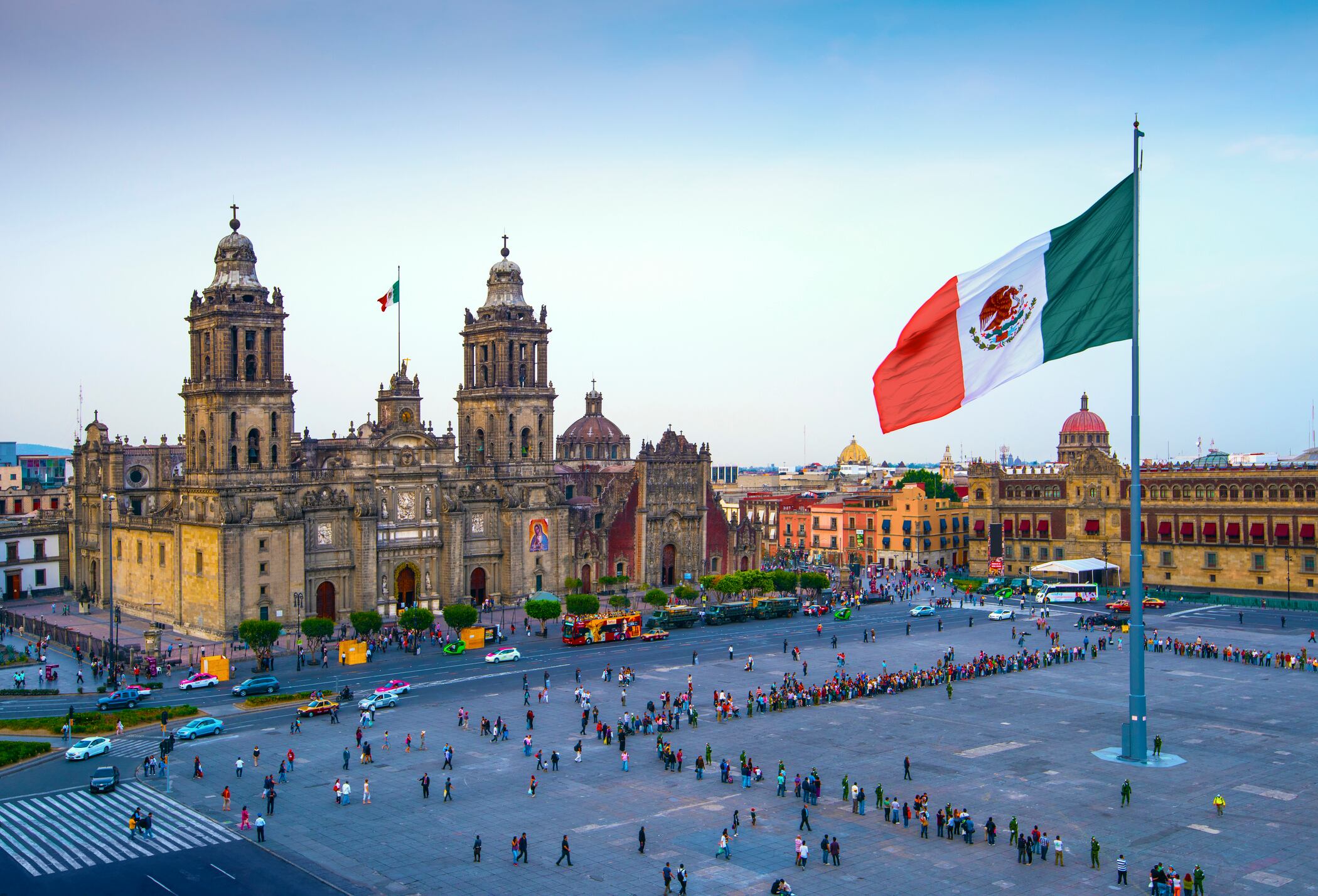 La bandera mexicana ondea sobre el Zócalo, la plaza principal de la Ciudad de México. La Catedral Metropolitana está frente a la plaza, también conocida como Plaza de la Constitución.