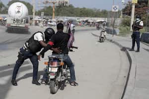 Un oficial de policía cachea a un motociclista en un puesto de control en Puerto Príncipe, Haití, el sábado 1 de julio de 2023.