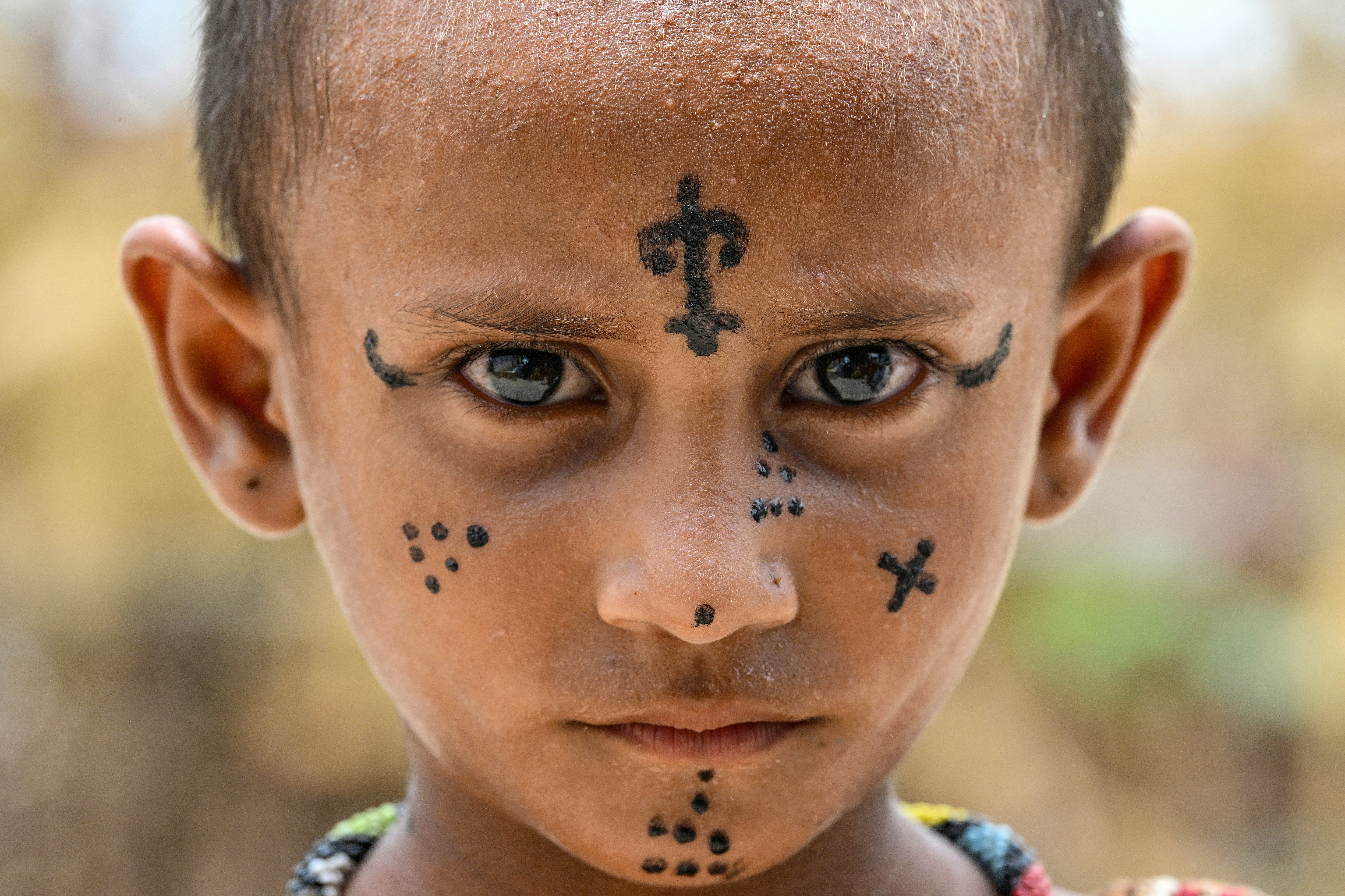 Pooja, de seis años, posa para la cámara mientras se adorna un tatuaje indígena en el rostro en la Colonia Jogi de Umerkot, un distrito de mayoría hindú en Pakistán. Foto de Asif HASSAN / AFP.