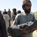 A man carries the body of his child, who was killed after a roof of a house collapsed, as he arrives for a burial following an earthquake in the remote mountainous district of Harnai on October 7, 2021, as around 20 people were killed and more than 200 injured when a shallow earthquake hit southwestern Pakistan in the early hours of October 7. (Photo by Banaras KHAN / AFP)