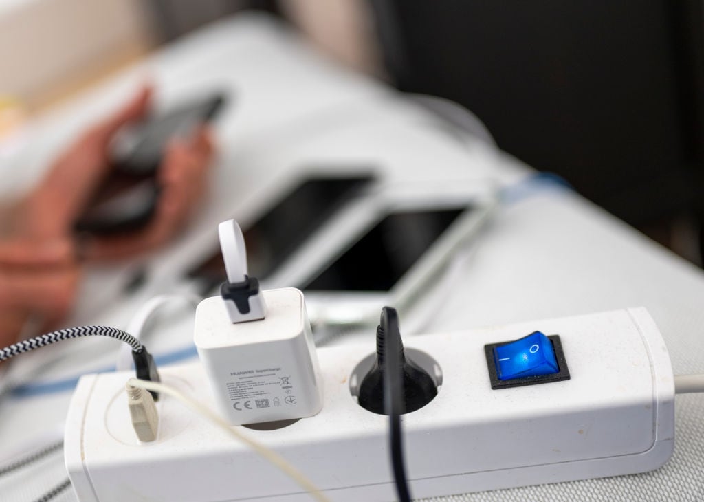 04 June 2022, Berlin: Numerous cables and chargers are plugged into a power strip while three smartphones are charging in the background. Photo: Monika Skolimowska/dpa (Photo by Monika Skolimowska/picture alliance via Getty Images)