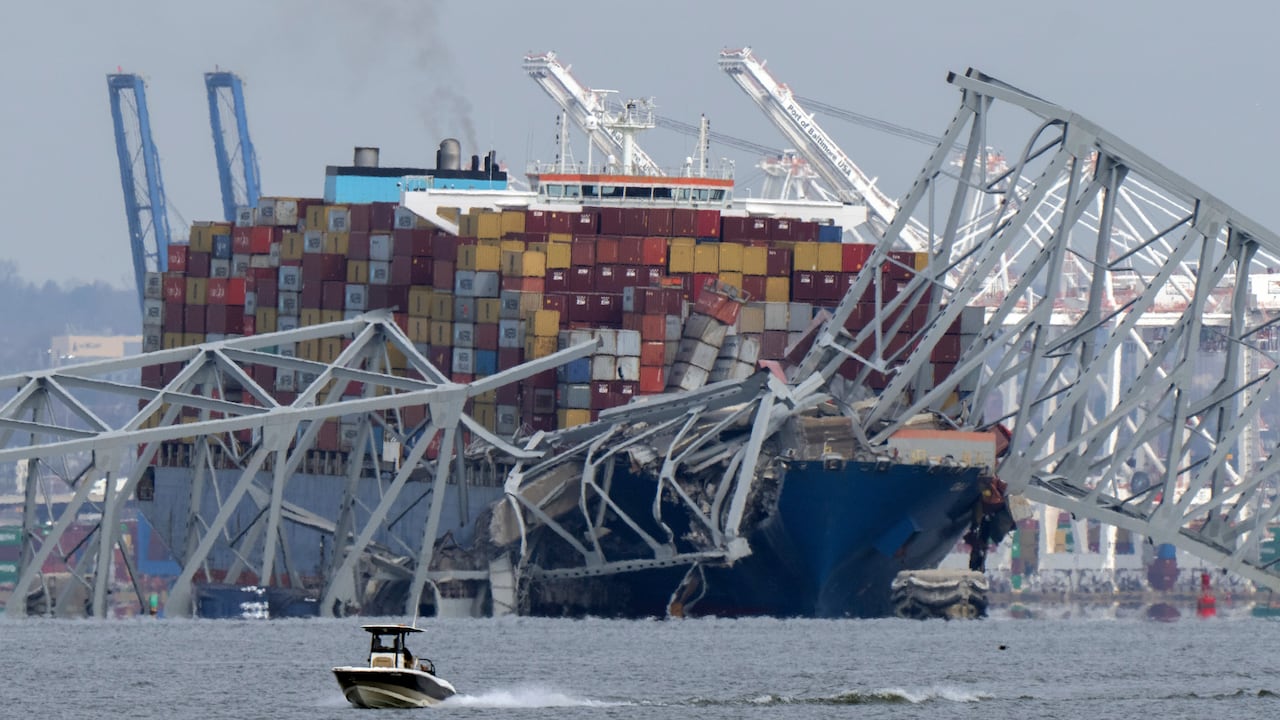 Un barco pasa frente a un buque portacontenedores que chocó contra el puente Francis Scott Key, el martes 26 de marzo de 2024, en Baltimore, Maryland. (Foto AP/Mark Schiefelbein)