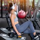 Fitness woman wearing sportwear and workout headband on in the gym. Woman is setting setup machine stationary bike screen options at gym.