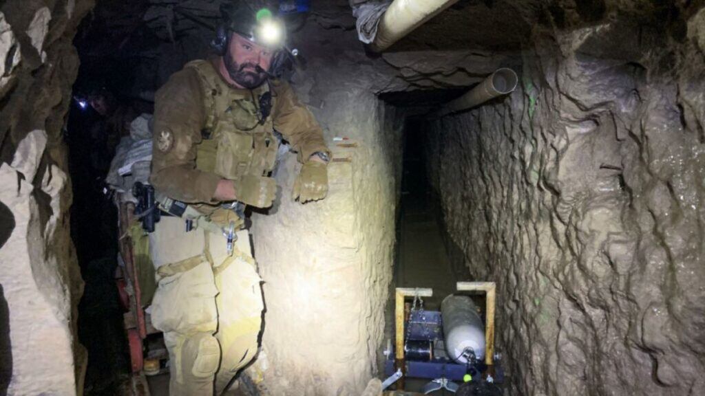 Elementos de seguridad exploran el túnel subterráneo que conecta Tijuana con San Diego, iluminado con linternas.