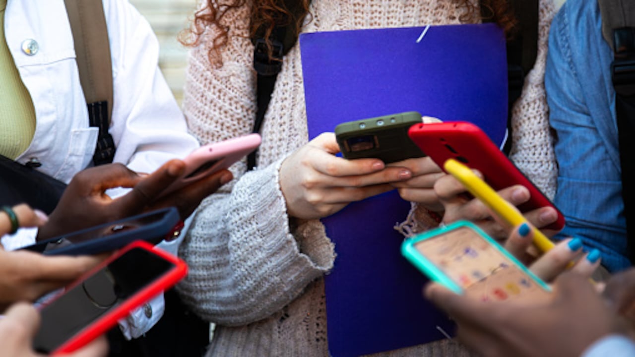Adolescentes adictos a los smartphones y la tecnología. Grupo de amigos compartiendo contenido en redes sociales. Concepto tecnológico.