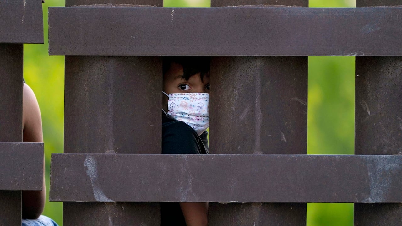 Un niño migrante mira a través del muro fronterizo entre Estados Unidos y México mientras un grupo es procesado y detenido cuando intentaban colarse a través de la frontera, en Abram-Perezville, Texas. Foto: AP / Julio Cortez.