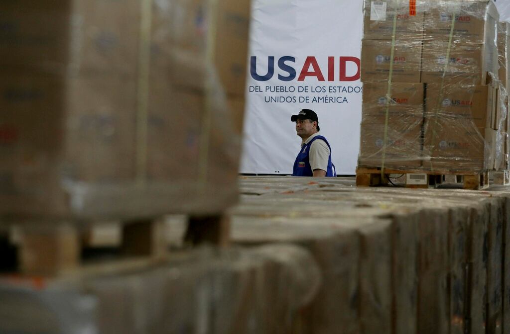 ARCHIVO - Un hombre pasa frente a cajas de ayuda humanitaria de USAID en un almacén en las afueras de Cúcuta, Colombia, el 21 de febrero de 2019, en la frontera con Venezuela. (AP Foto/Fernando Vergara)