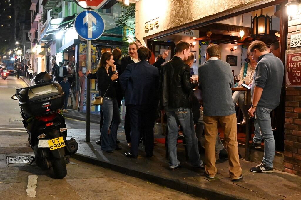 La gente se reúne frente a un bar en Hong Kong el 6 de enero de 2022, antes del cierre del 7 de enero de gimnasios, bares y cenas en restaurantes por la noche tras el anuncio de nuevos controles estrictos contra el coronavirus después de que se detectara la variante Omicron. (Foto de Peter PARKS / AFP)
