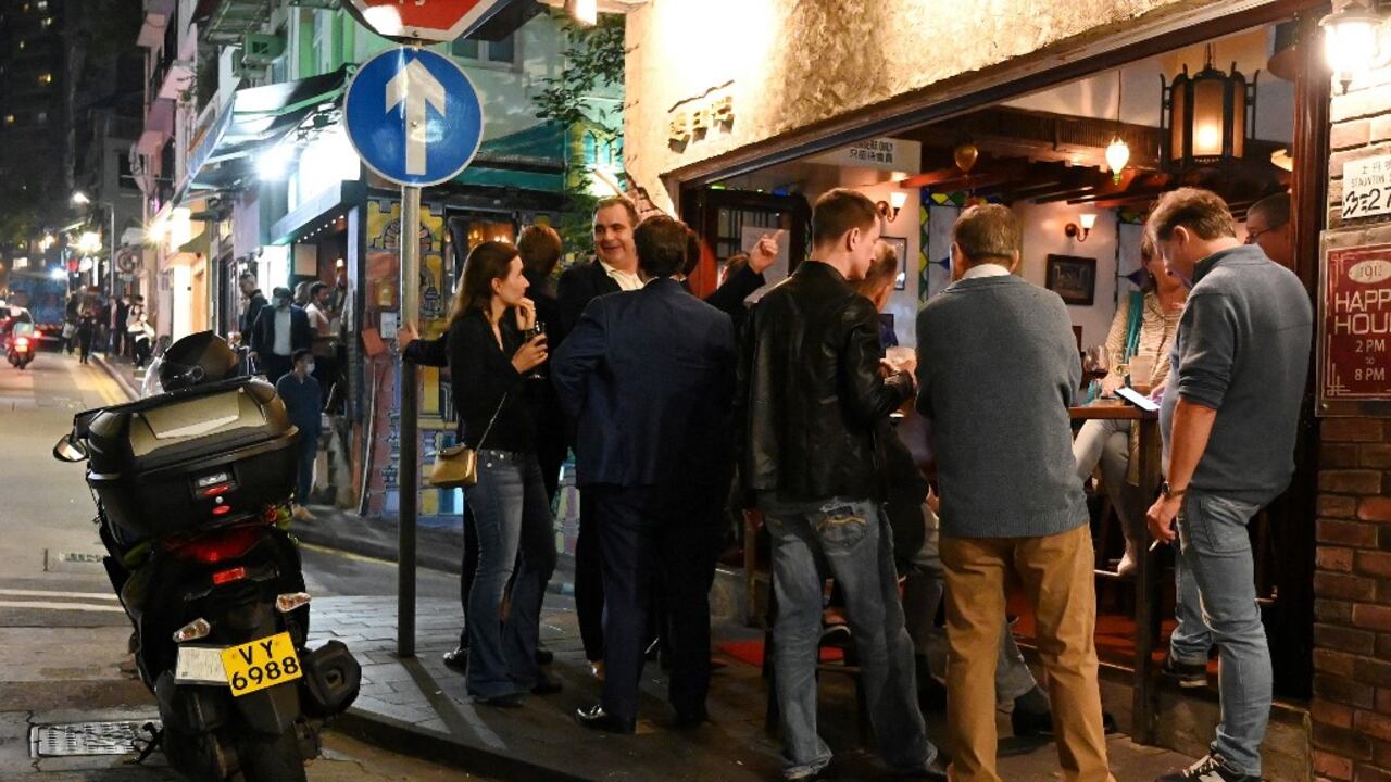 La gente se reúne frente a un bar en Hong Kong el 6 de enero de 2022, antes del cierre del 7 de enero de gimnasios, bares y cenas en restaurantes por la noche tras el anuncio de nuevos controles estrictos contra el coronavirus después de que se detectara la variante Omicron. (Foto de Peter PARKS / AFP)