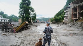 Un policía con un perro rastreador observa los daños tras las inundaciones repentinas en Devighat, en el distrito de Nuwakot, Nepal, el jueves 27 de agosto de 2026. (Foto AP/Niranjan Shrestha)