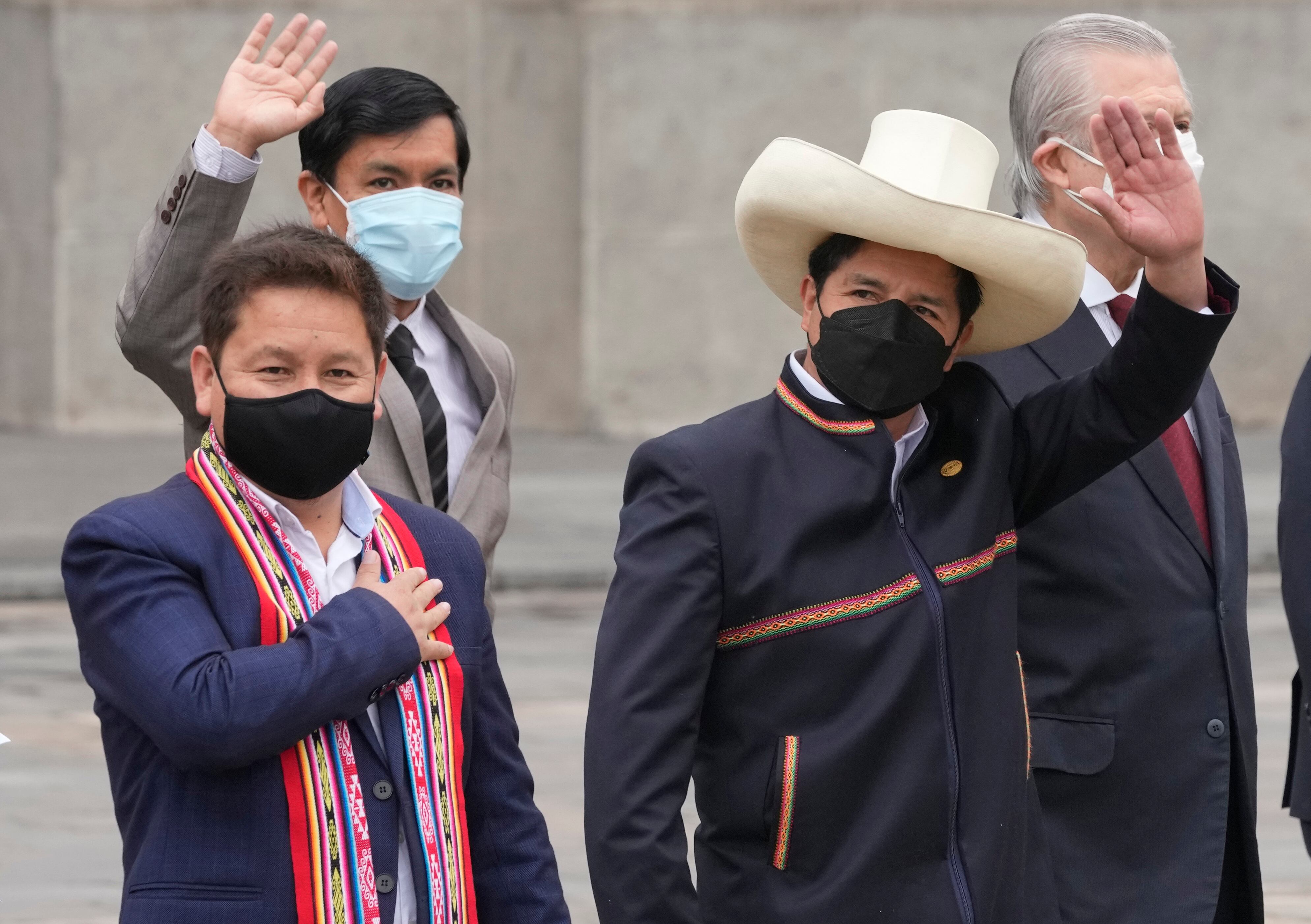 El presidente peruano Pedro Castillo, a la derecha, saluda junto al primer ministro Guido Bellido, a la izquierda, y los miembros de su gabinete en el palacio de gobierno mientras Bellido y el gabinete parten hacia el Congreso para pedirle a los legisladores un voto de confianza en Lima, Perú, el jueves 26 de agosto de 2021. (AP Foto/Martín Mejía)