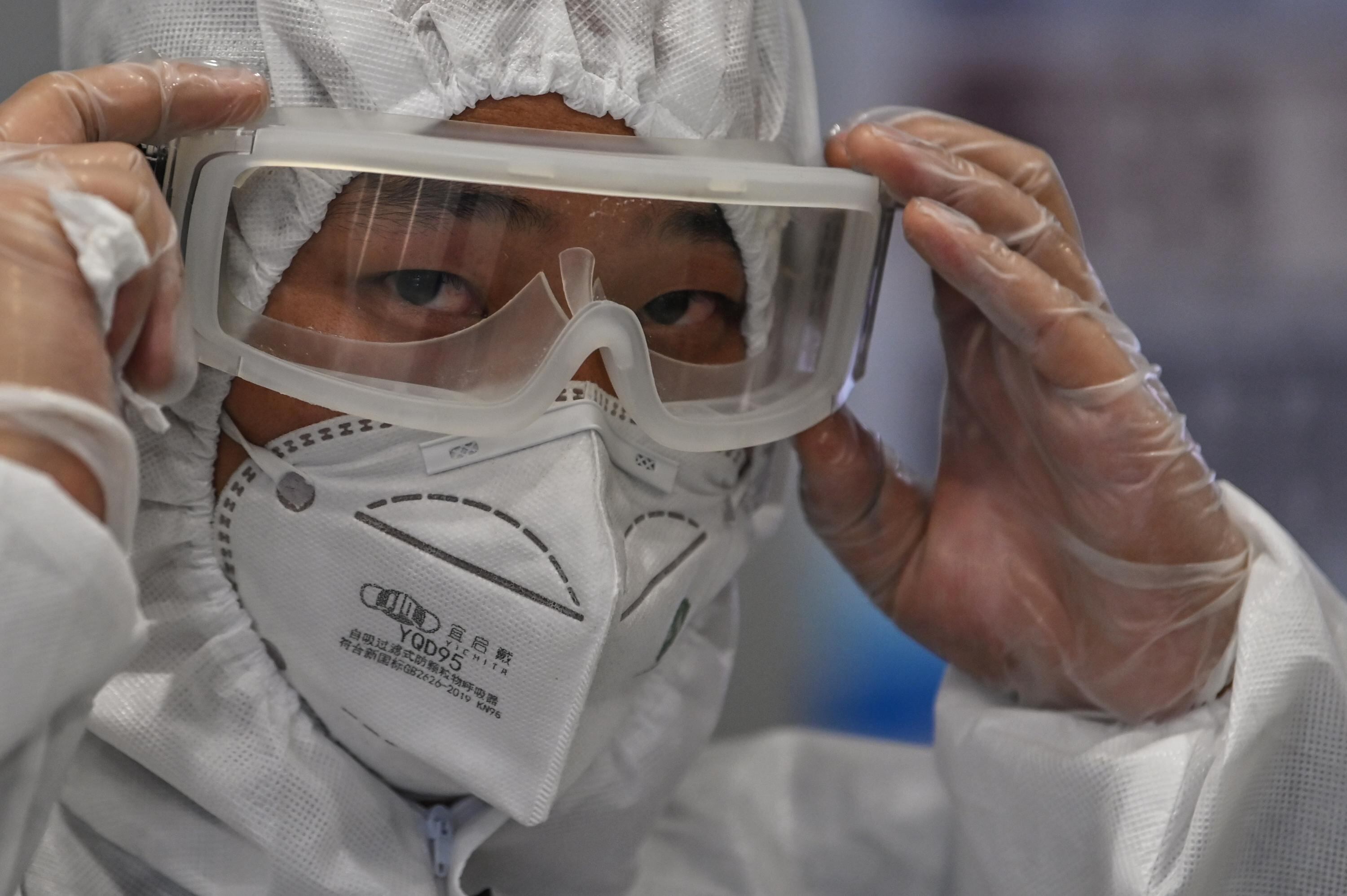Un hombre usa traje protector, tapabocas y gafas en el Aeropuerto Internacional de Shanghai, China.