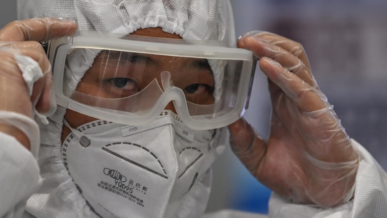 Un hombre usa traje protector, tapabocas y gafas en el Aeropuerto Internacional de Shanghai, China.