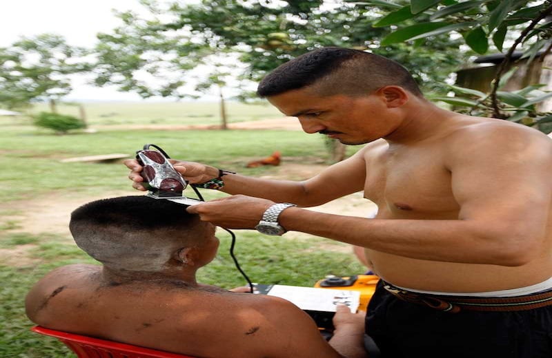 Andrés González (32 años), del frente Combatientes del Yarí, le sirve de peluquero de emergencia a un campesino de la región.
