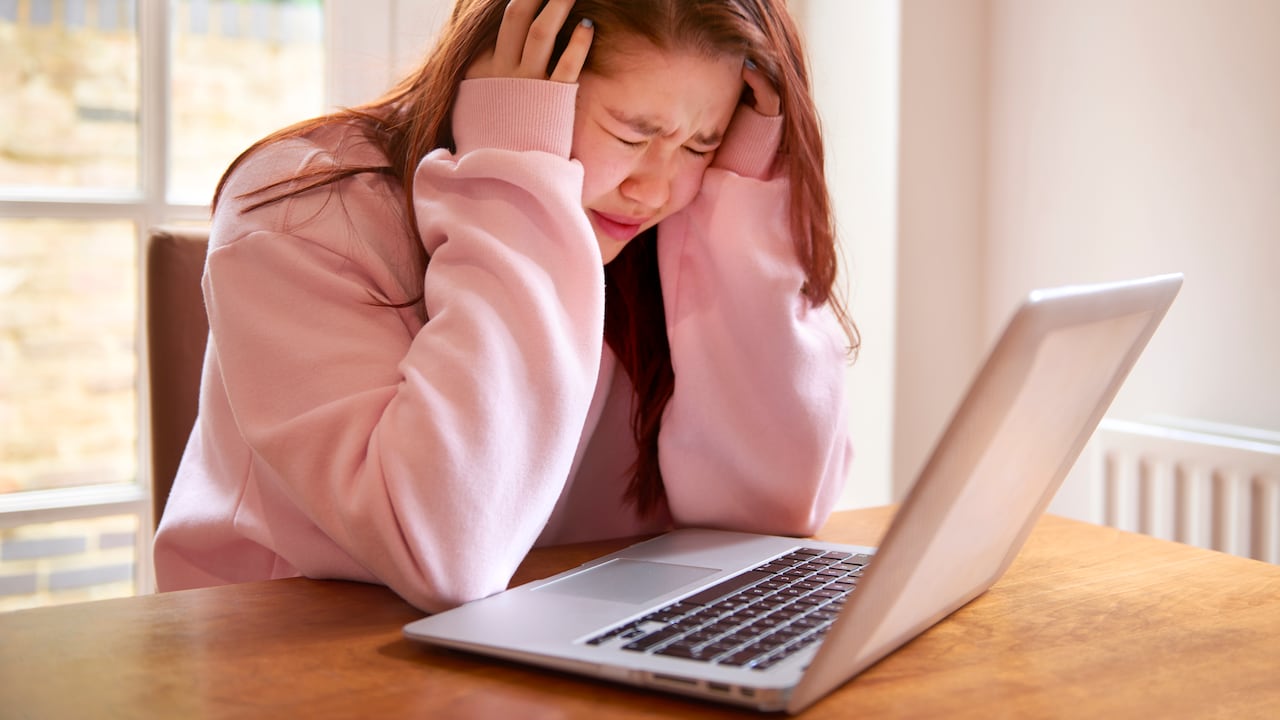 student girl with eyes closed and head in hands crying