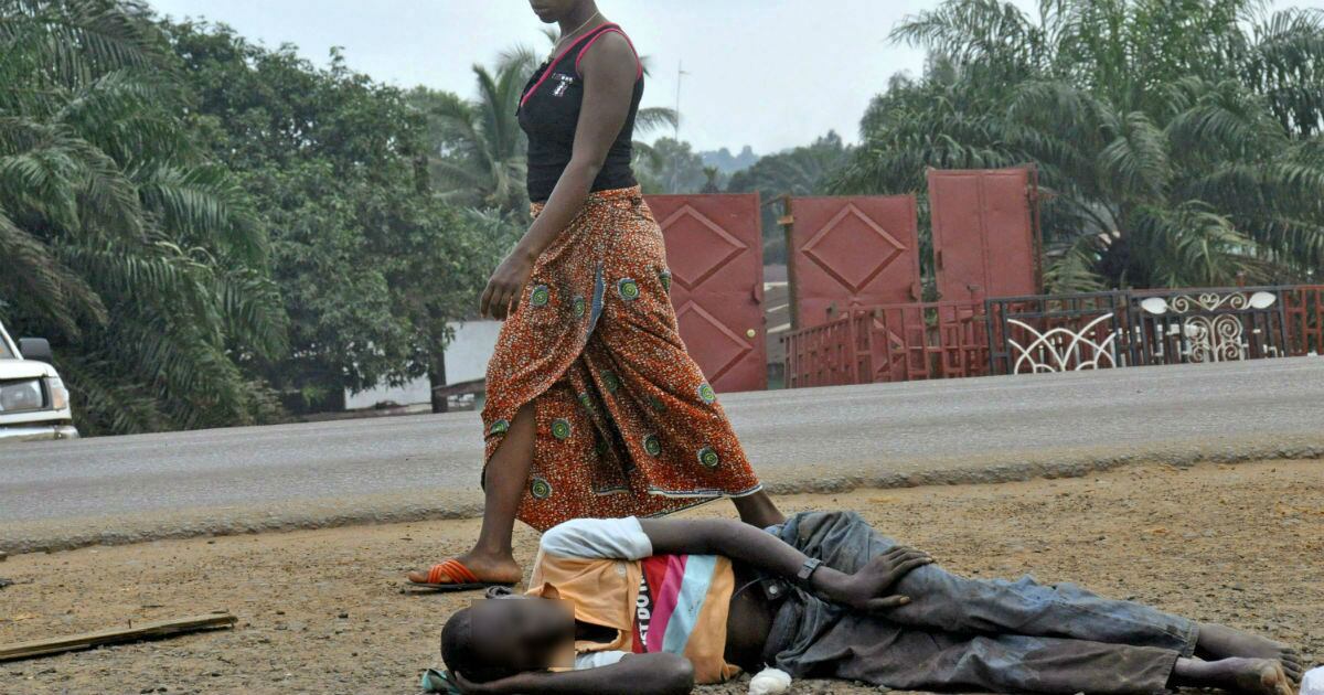 Una mujer pasa cerca del cuerpo de un hombre de quien se sospecha murió a causa del ébola, en Monrovia, Liberia.