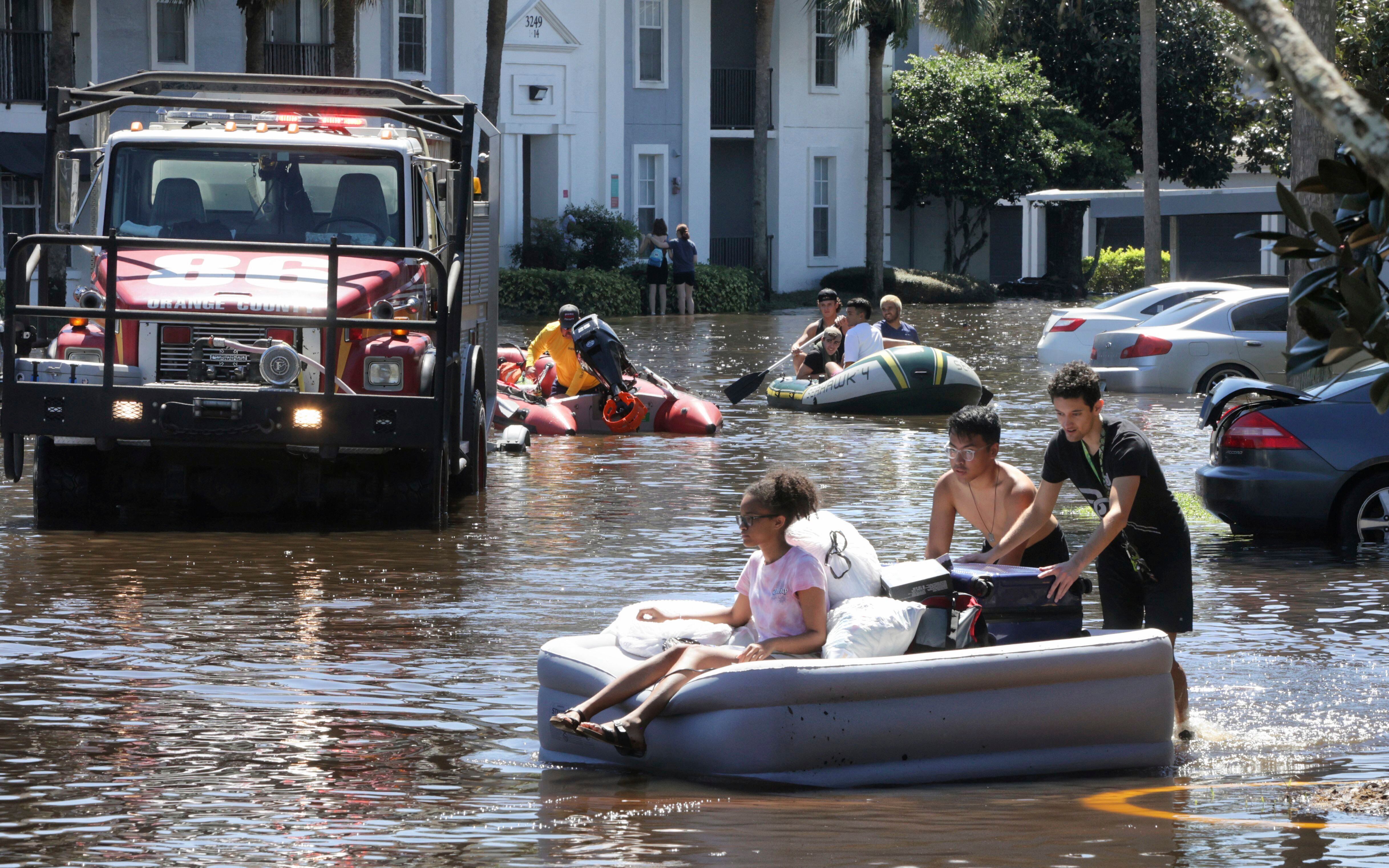 Estudiantes de la Universidad Central de Florida usan un colchón inflable para evacuar un complejo de apartamentos que quedó inundado por la lluvia del huracán Ian. (Joe Burbank/Orlando Sentinel vía AP)