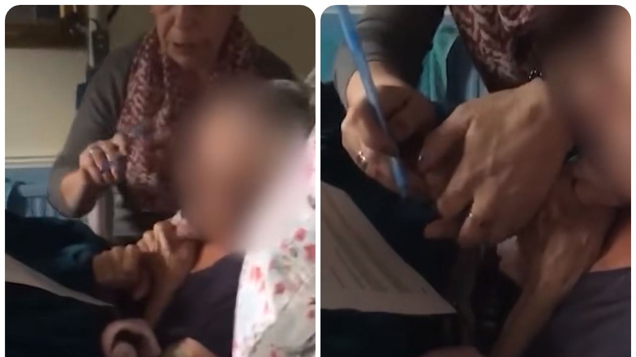 La mujer pone un bolígrafo en la mano de su madre para firmar el documento