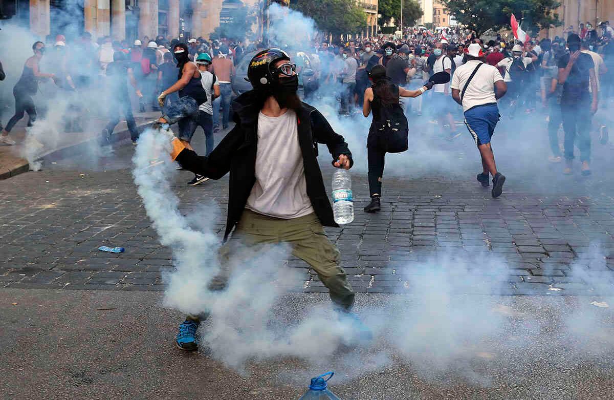 Los manifestantes arrojan gas lacrimógeno hacia los policías antidisturbios durante una protesta contra el gobierno, a raíz de la explosión masiva del martes pasado que devastó Beirut.  AP Photo/Bilal Hussein.