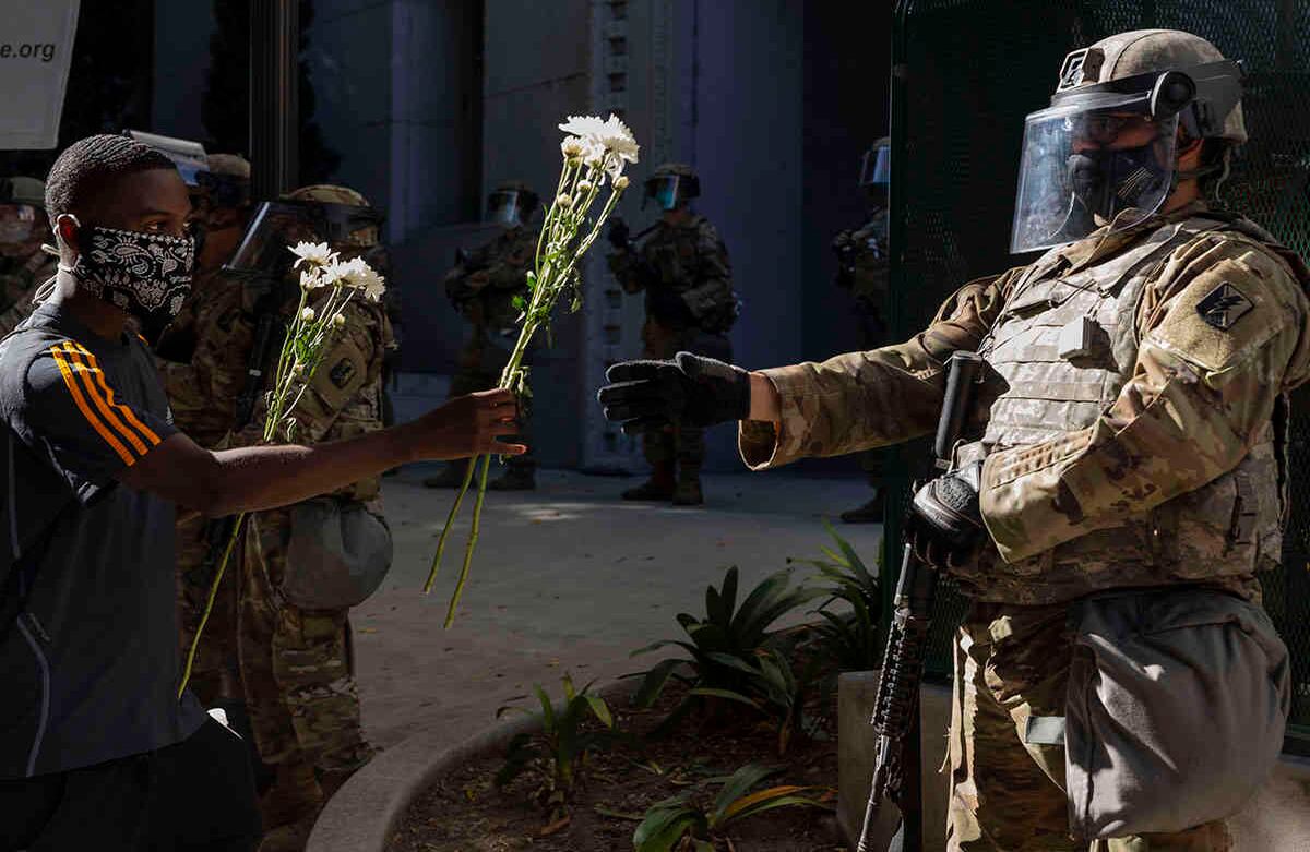 Un manifestante ofrece flores a un guardia nacional estacionado frente a la oficina de la fiscal del condado de Los Ángeles, Jackie Lacey, el 3 de junio, durante una protesta por la muerte de George Floyd, quien murió el 25 de mayo después de ser capturado y sometido a agresiones por la policía de Minneapolis. Foto: Damian Dovarganes/ AP