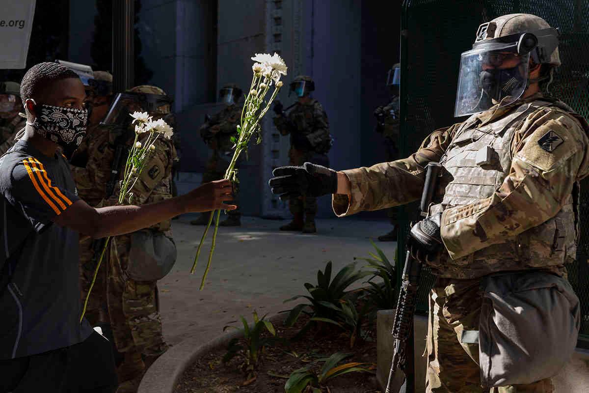 Un manifestante ofrece flores a un guardia nacional estacionado frente a la oficina de la fiscal del condado de Los Ángeles, Jackie Lacey, el 3 de junio, durante una protesta por la muerte de George Floyd, quien murió el 25 de mayo después de ser capturado y sometido a agresiones por la policía de Minneapolis. Foto: Damian Dovarganes/ AP