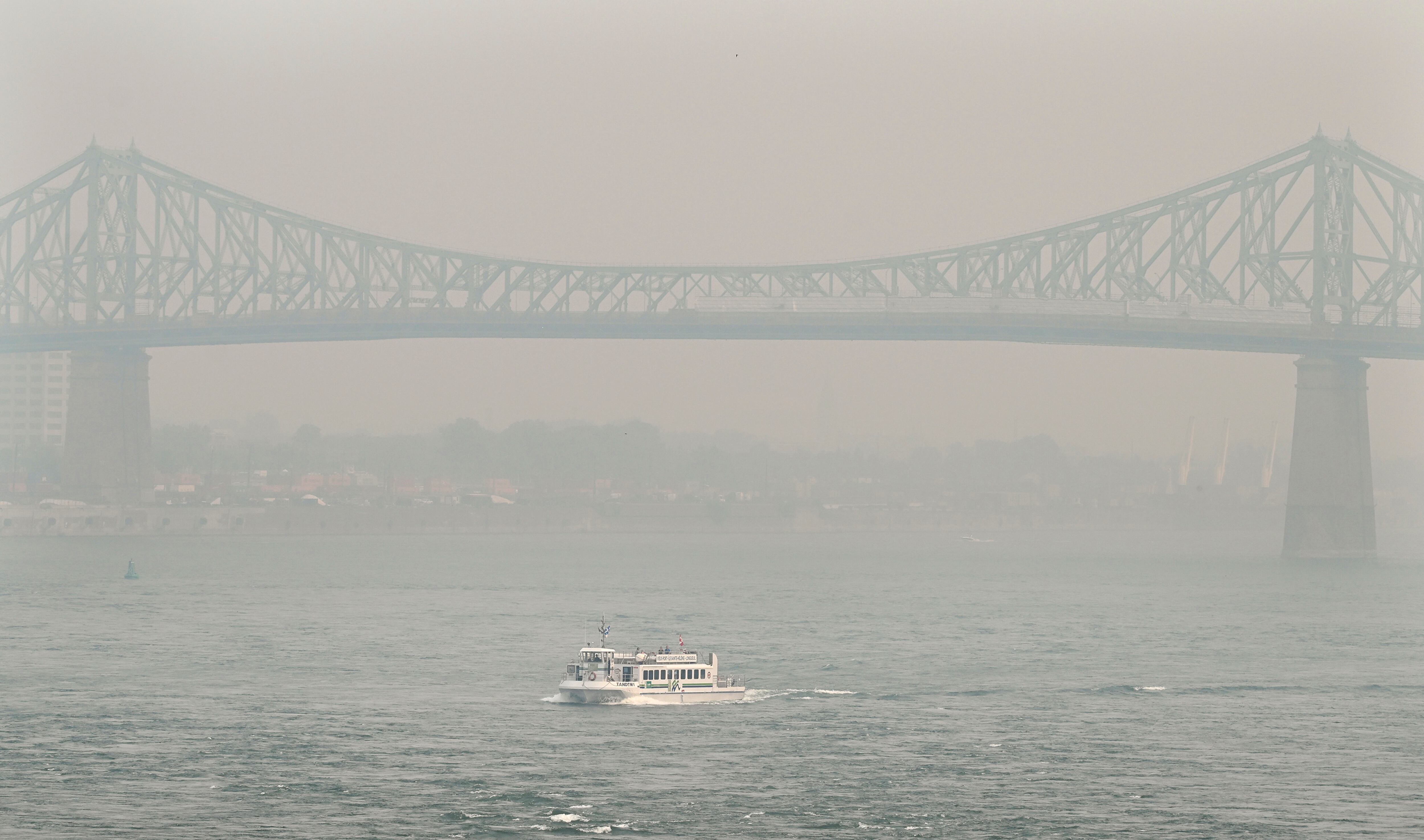 Un bote pasa por el puente Jacques Cartier oscurecido por una neblina de smog en Montreal, el domingo 25 de junio de 2023, mientras una advertencia de smog está vigente para la ciudad y varias regiones de la provincia debido a incendios forestales.