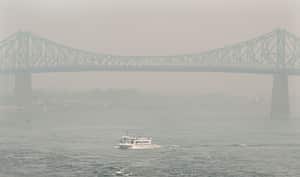 Un bote pasa por el puente Jacques Cartier oscurecido por una neblina de smog en Montreal, el domingo 25 de junio de 2023, mientras una advertencia de smog está vigente para la ciudad y varias regiones de la provincia debido a incendios forestales.