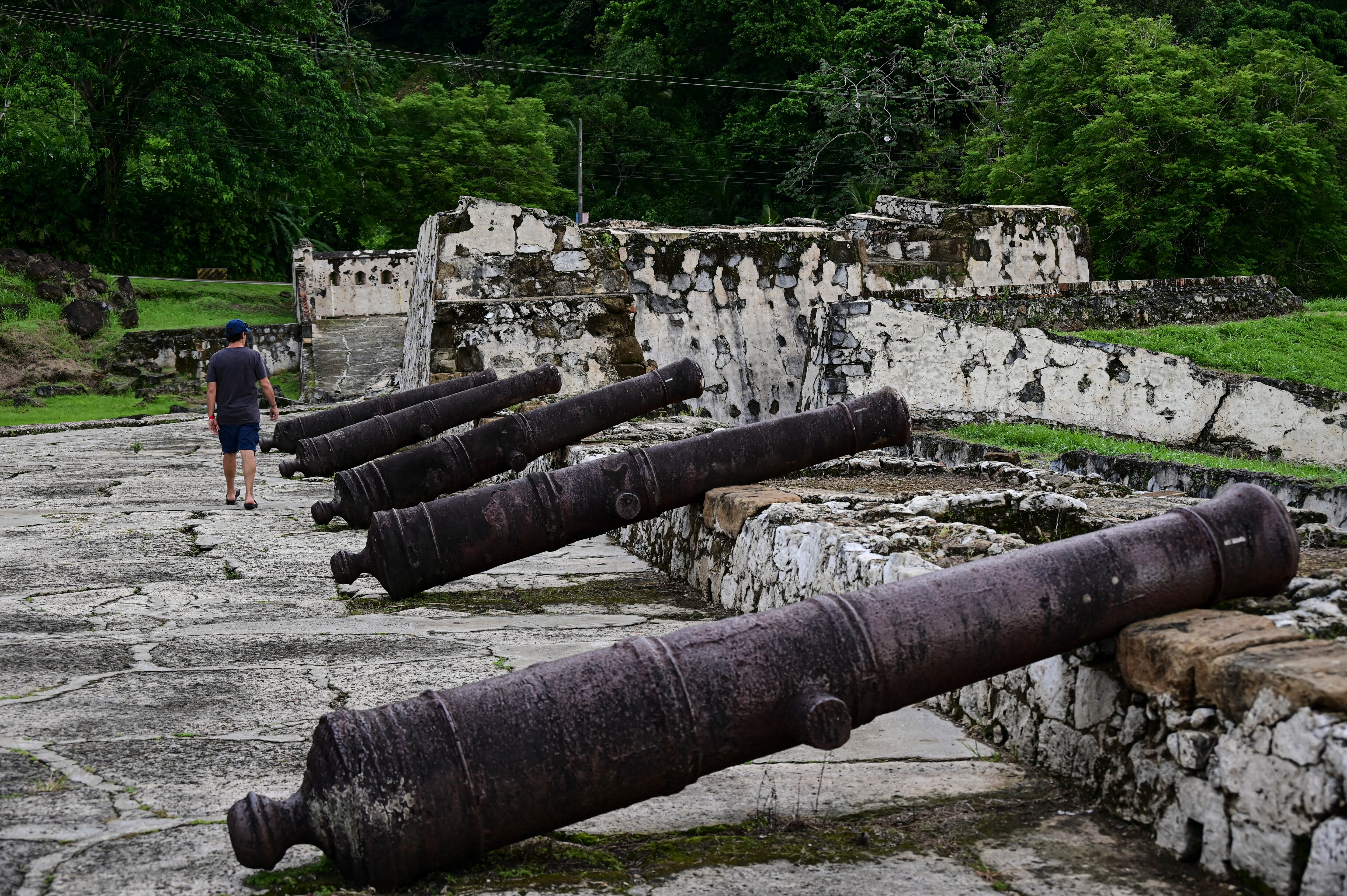 (ARCHIVOS) Un hombre camina junto a los cañones de la fortificación española de Portobelo en Portobelo, Panamá, 25 de mayo de 2024. El 12 de julio de 2025, la ruta colonial de Panamá, históricamente utilizada para transportar las riquezas de América en mula y barco durante siglos y que sirvió como precursora del canal interoceánico, fue designada Patrimonio de la Humanidad por la UNESCO. (Foto de MARTIN BERNETTI / AFP)
