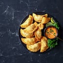 delicious deep fried Buffalo Chicken Empanadas with Low Calorie Dip on a black platter on a concrete table, horizontal view from above, flat lay, free space