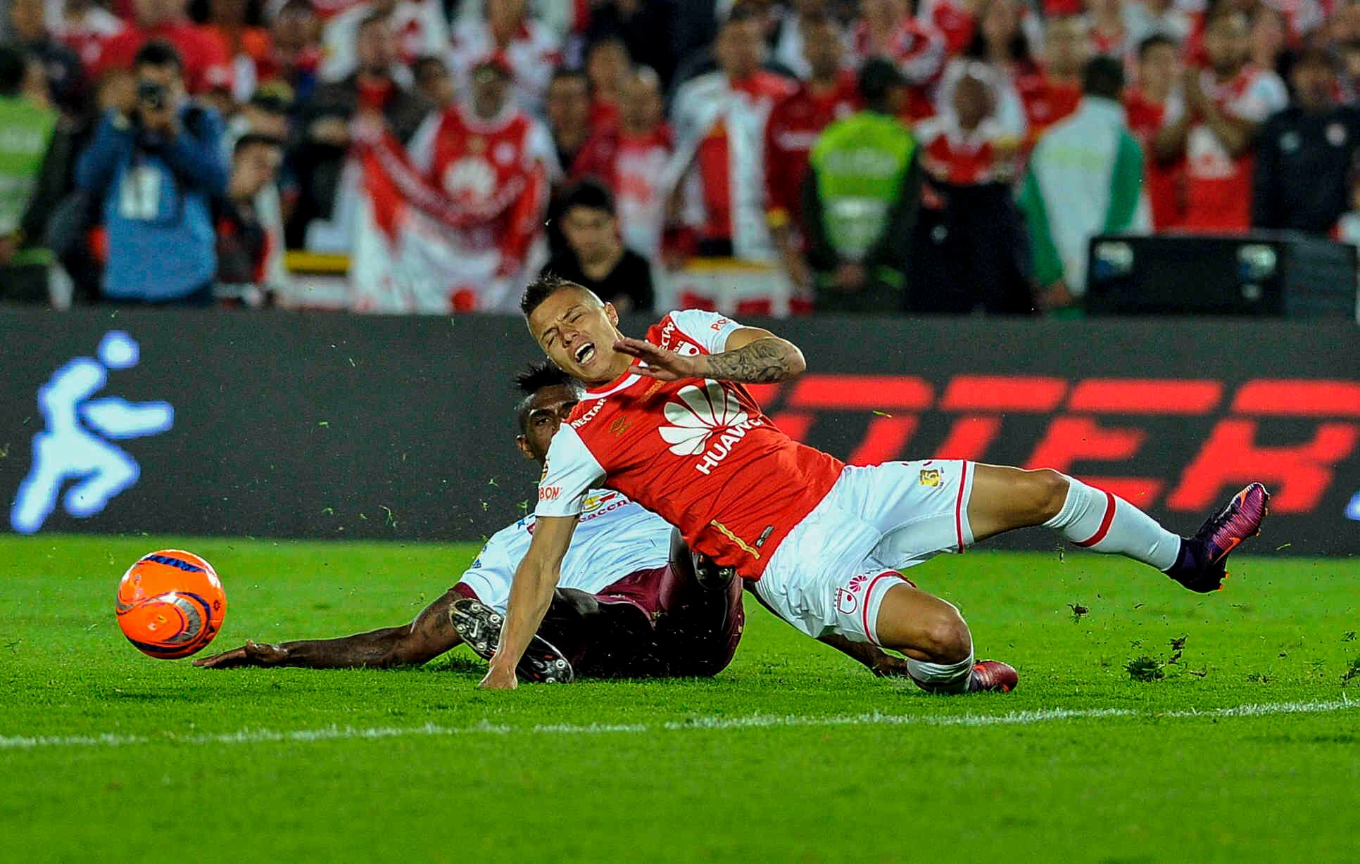 Sergio Mosquera, del Tolima (atrás) comete falta contra John Freddy Salazar durante el partido de vuelta frente al Tolima, el domingo 18 de diciembre de 2016, en el Campín, en Bogotá. Al pitazo final los cardenales derrotaron 1-0 a los tolimenses con un gol de Héctor Urrego y lograron su novena estrella en el torneo profesional de fútbol colombiano
