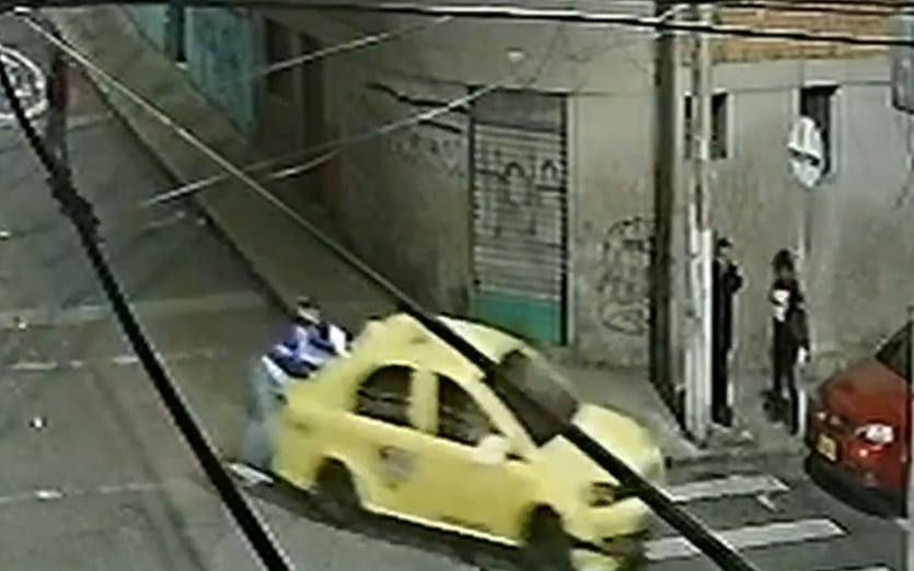 Instante en que el motociclista cae del techo del taxi en una curva.