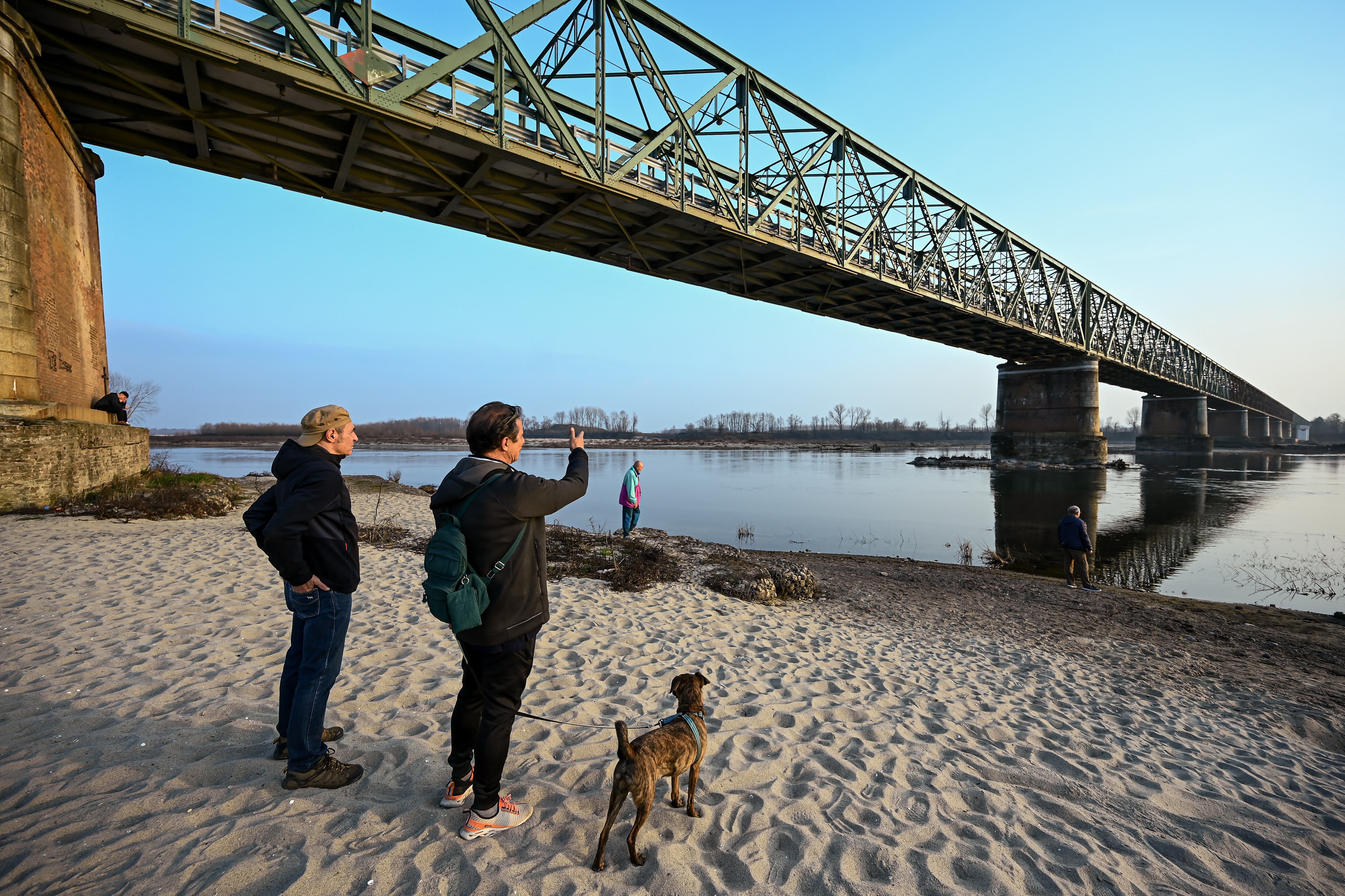 La gente toma fotos junto al lecho del río Po el 21 de febrero de 2023 en Ponte della Becca, en Linarolo, cerca de Pavía. - La falta de nieve en los picos de las montañas circundantes, la ausencia de lluvia durante las últimas seis semanas y las temperaturas suaves: este cóctel explosivo ha provocado que el nivel del agua del lago más grande de Italia caiga a su nivel más bajo en 30 años durante los meses de invierno. (Foto de Piero CRUCIATTI / AFP)