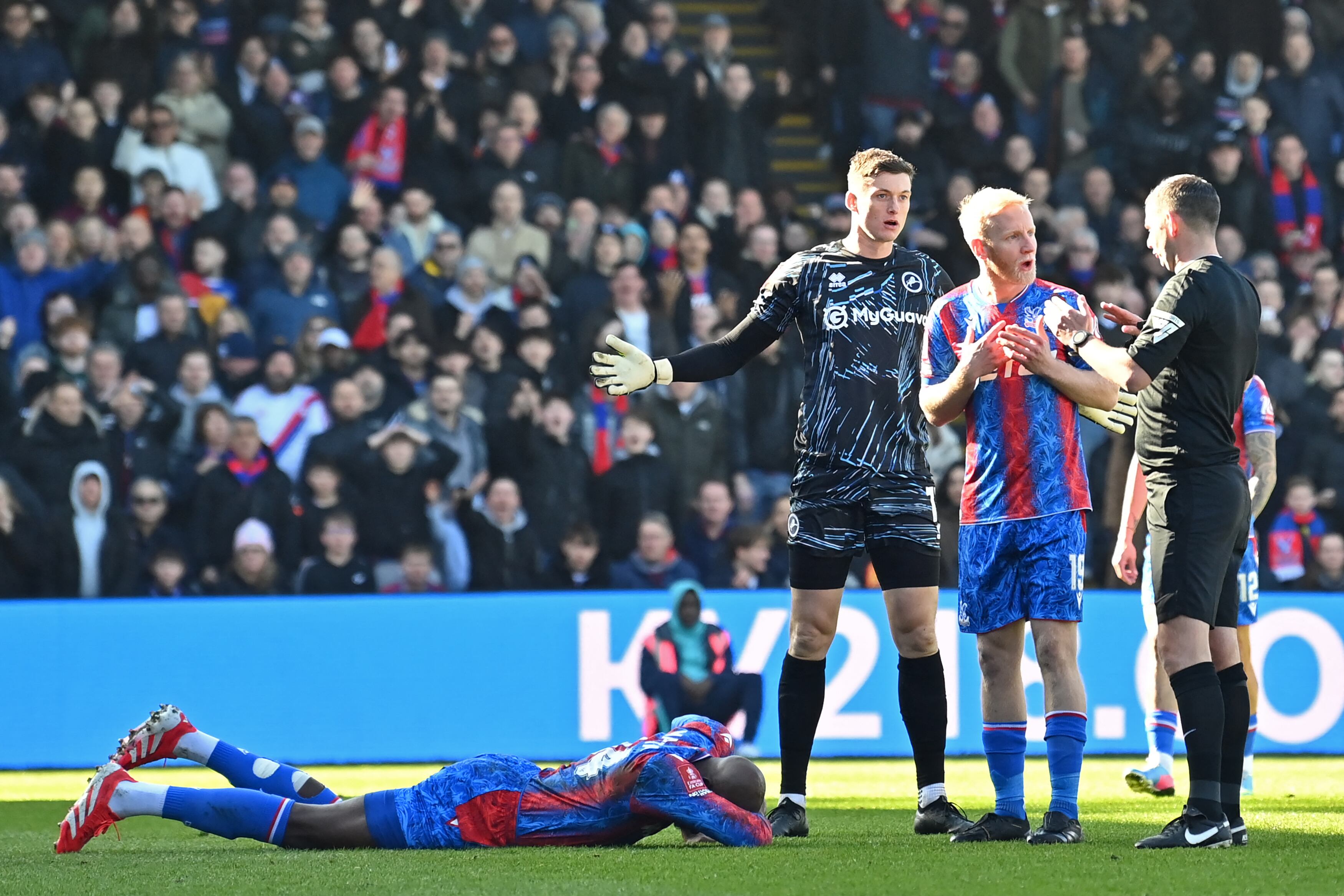 Crystal Palace's French striker #14 Jean-Philippe Mateta (L) lies injured after a dangerous challenge from Millwall's English goalkeeper #13 Liam Roberts (3R) during the English FA Cup fifth round football match between Crystal Palace and Millwall at Selhurst Park in south London on March 1, 2025. (Photo by Glyn KIRK / AFP) / RESTRICTED TO EDITORIAL USE. No use with unauthorized audio, video, data, fixture lists, club/league logos or 'live' services. Online in-match use limited to 120 images. An additional 40 images may be used in extra time. No video emulation. Social media in-match use limited to 120 images. An additional 40 images may be used in extra time. No use in betting publications, games or single club/league/player publications. /
