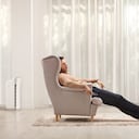 Joven durmiendo en un sillón frente a un televisor en casa