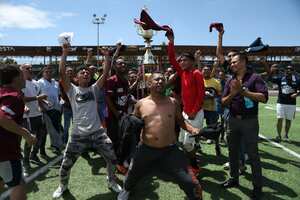 Venezuelan migrants celebrate with the trophy after winning the championship during the "Copa America Migrante 2023" football tournament in Ciudad Juarez, Chihuahua state, Mexico, on August 3, 2023. (Photo by Herika Martinez / AFP)