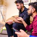 friends from india looking something interesting on laptop in livingroom.