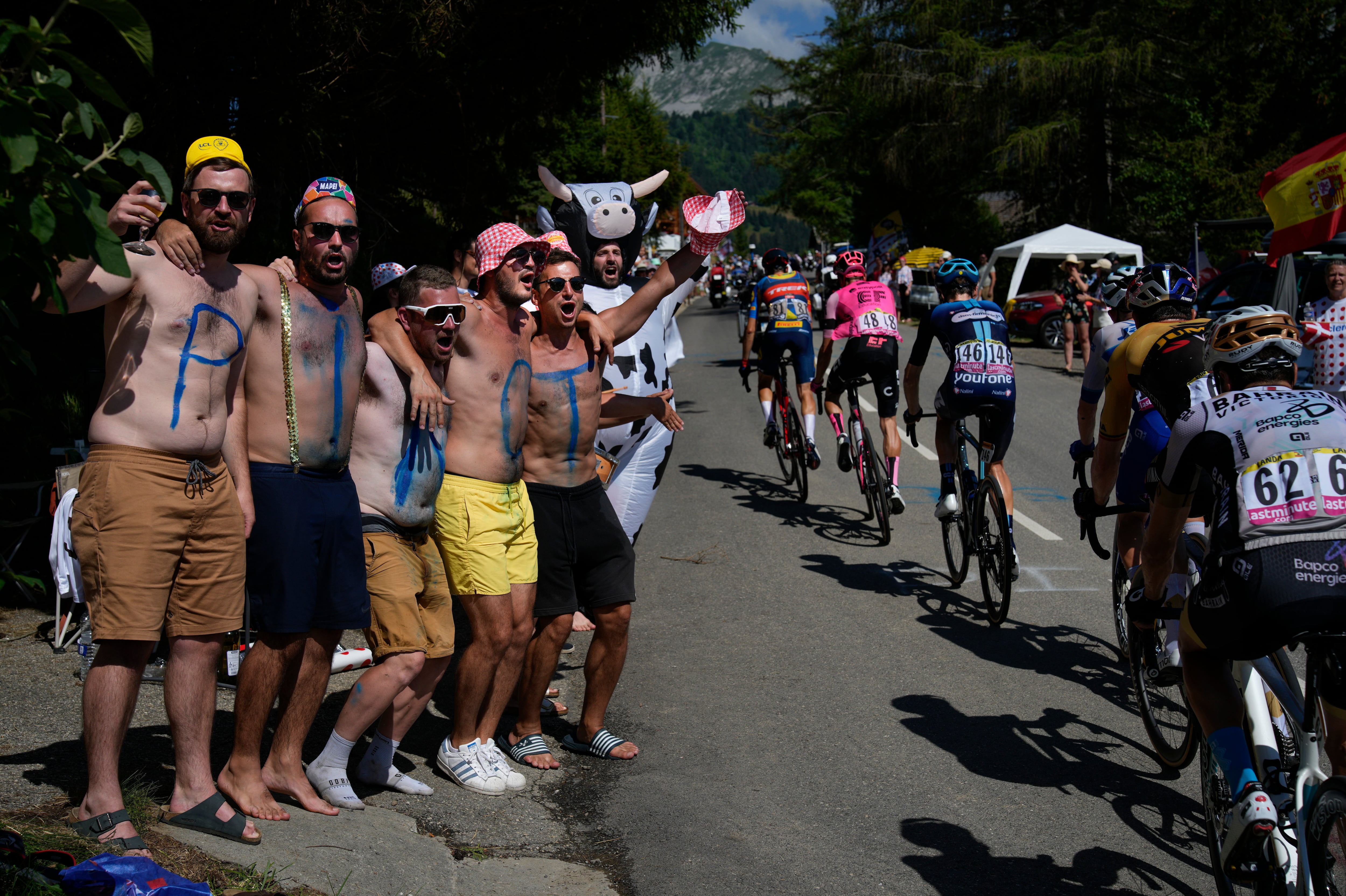 Cyclings fans and supporters of France's Thibault Pinot, each with one letter of his last name on their body, cheer as the breakaway group passes during the fifteenth stage of the Tour de France cycling race over 179 kilometers (111 miles) with start in Les Gets Les Portes du Soleil and finish in Saint-Gervais Mont-Blanc, France, Sunday, July 16, 2023. (AP Photo/Daniel Cole)