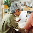 Rear view of casually clothed senior couple going over paperwork at home