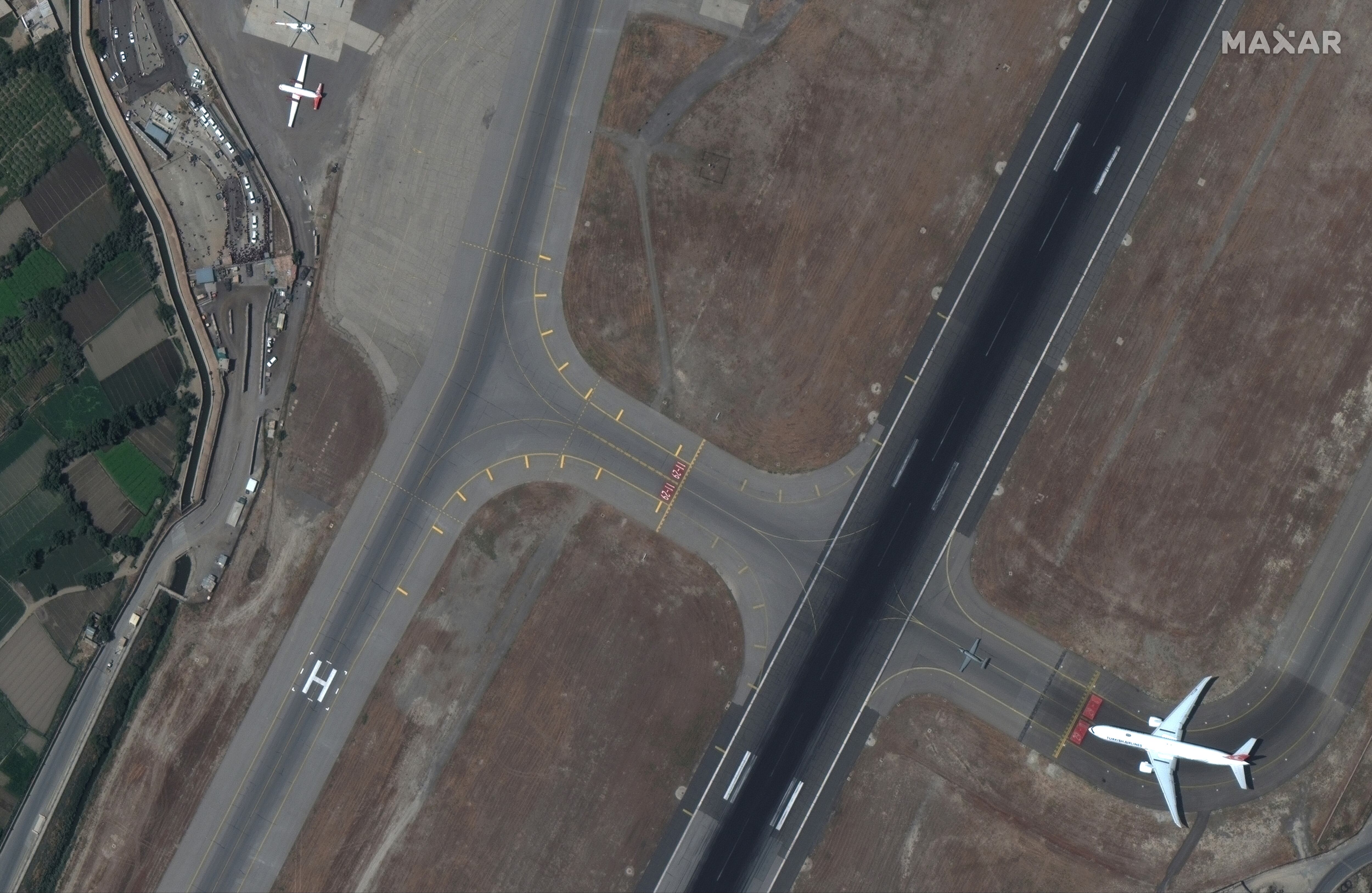 Las multitudes de personas y seguridad se ven cerca de la pista en el aeropuerto de Kabul en Afganistán.