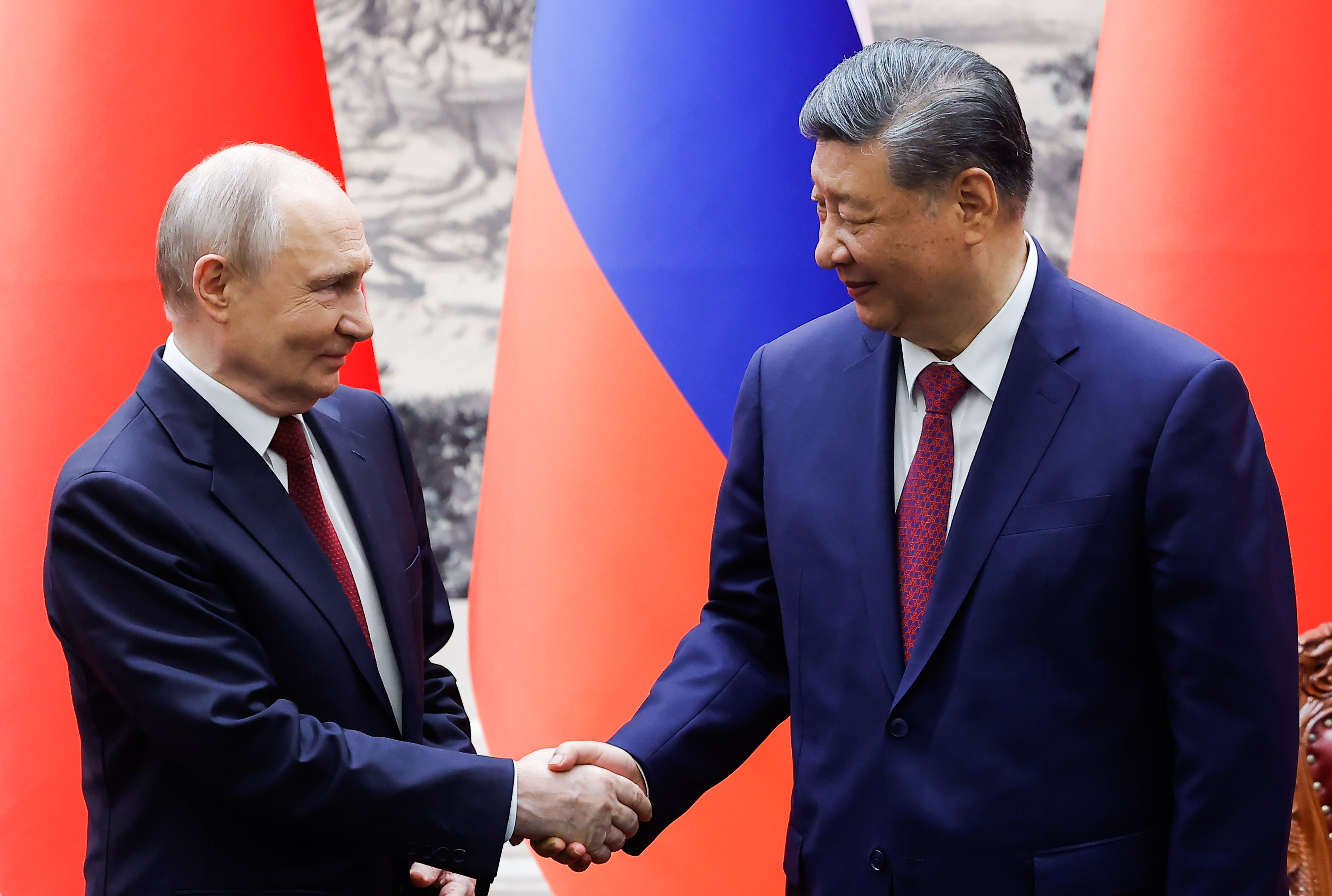 El presidente ruso Vladimir Putin, a la izquierda, y el presidente chino Xi Jinping se dan la mano durante una ceremonia de firma en el Gran Salón del Pueblo en Pekín